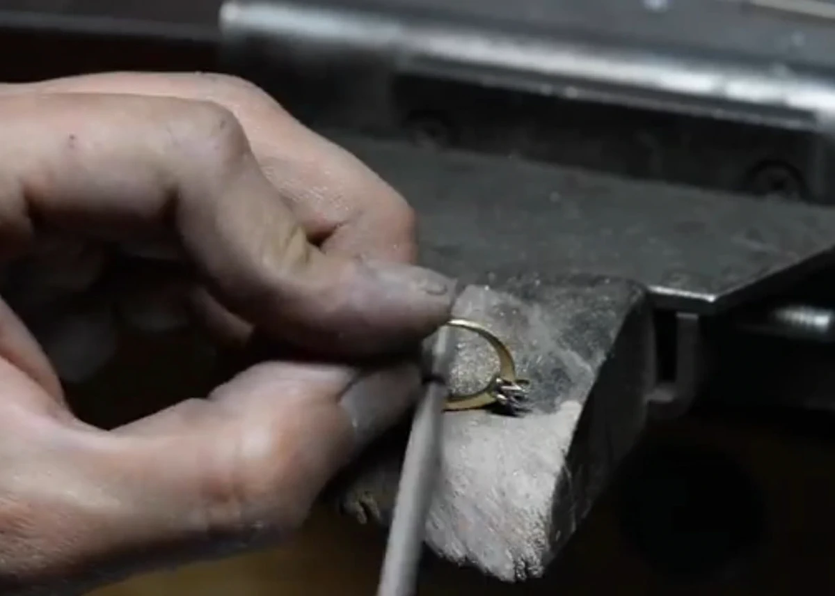 Manos de un artesano puliendo un anillo de oro en el banco de trabajo